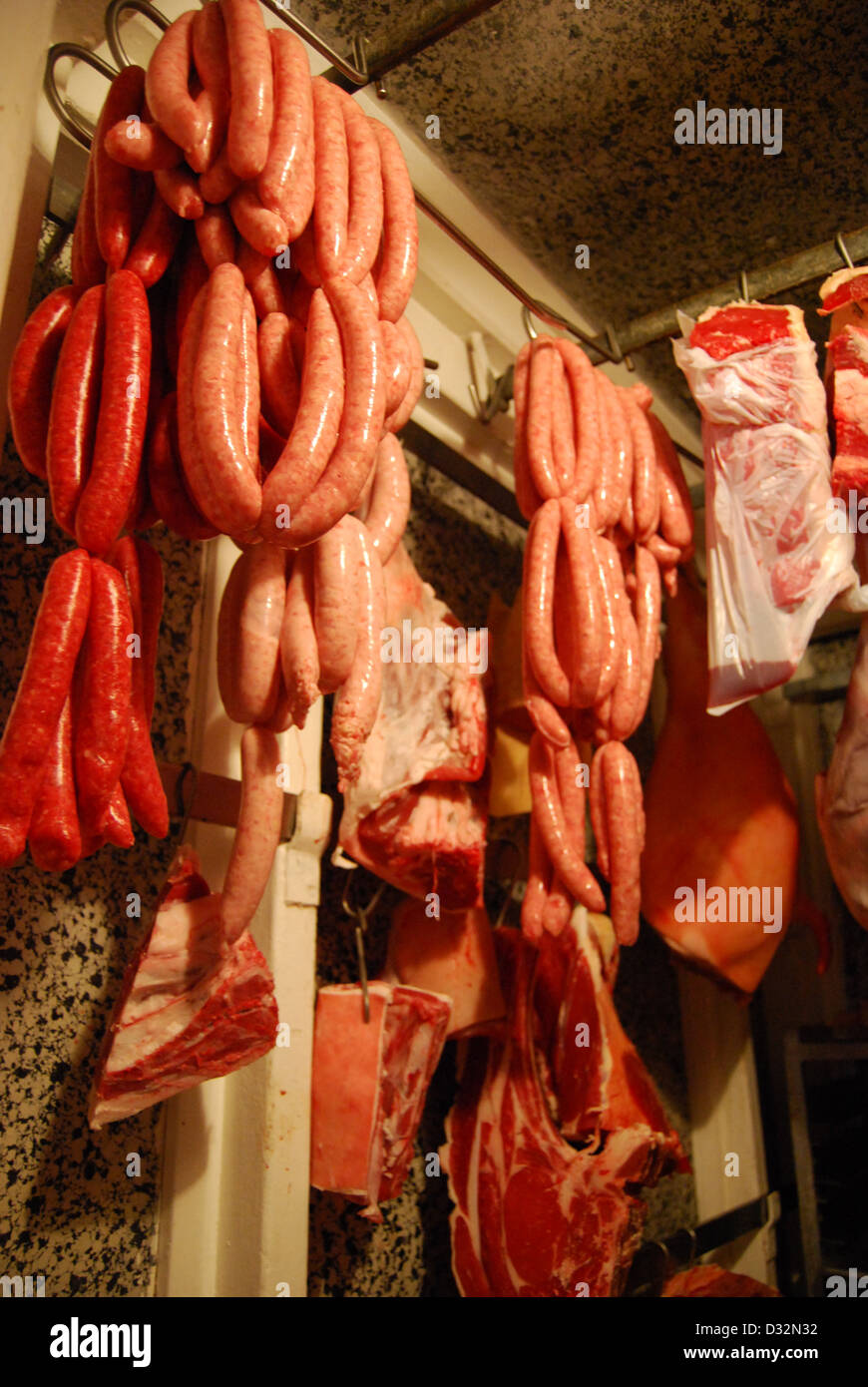 Platten von Fleisch und Wurstwaren, Schwein, Lamm, weißem und rotem Fleisch hängen in einem Metzger Kühllagerung warten darauf geschnitten und sortiert werden. Stockfoto