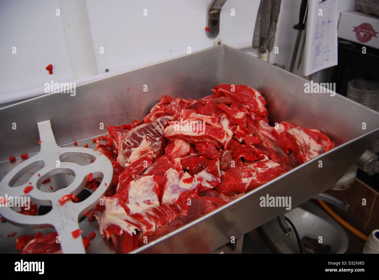 Rotes Fleisch Platten auf einem unordentlichen Metzger Tisch in ein Metall Edelstahl Knochen Grinder bereit, geschnitten und sortiert werden. Stockfoto