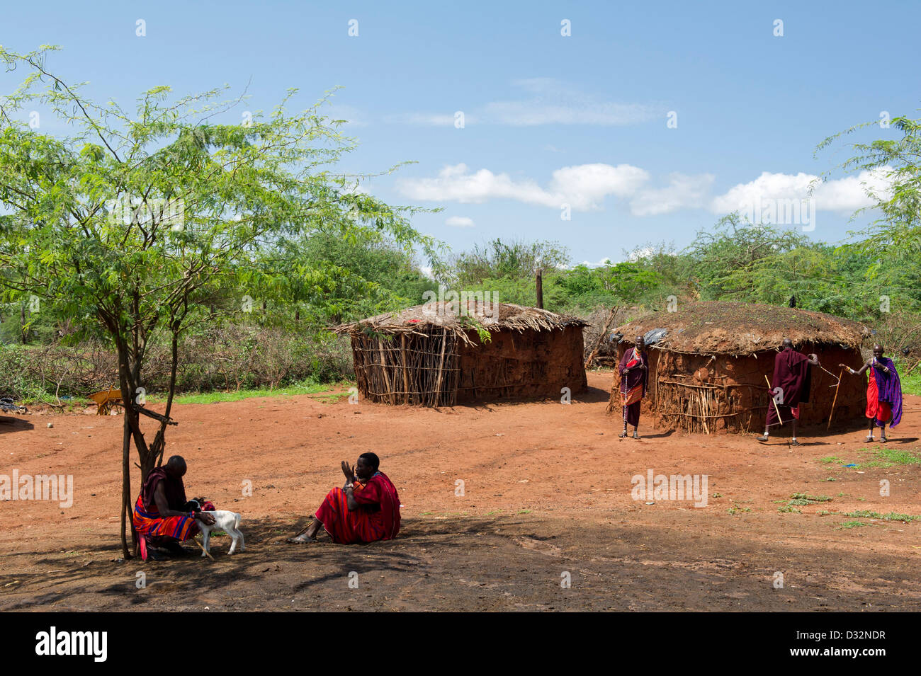 Maasai-Männer und urige Hütten in der Manyatta, Kenia Stockfoto