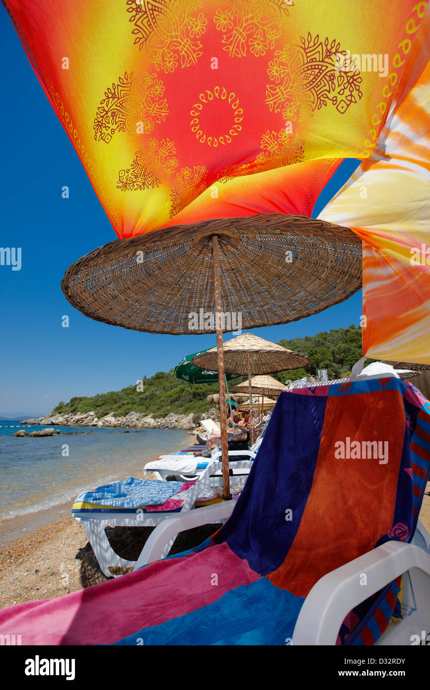 Liegestuhl unter buntem Baldachin am Strand. Torba Dorf, Halbinsel Bodrum, Türkei. Stockfoto