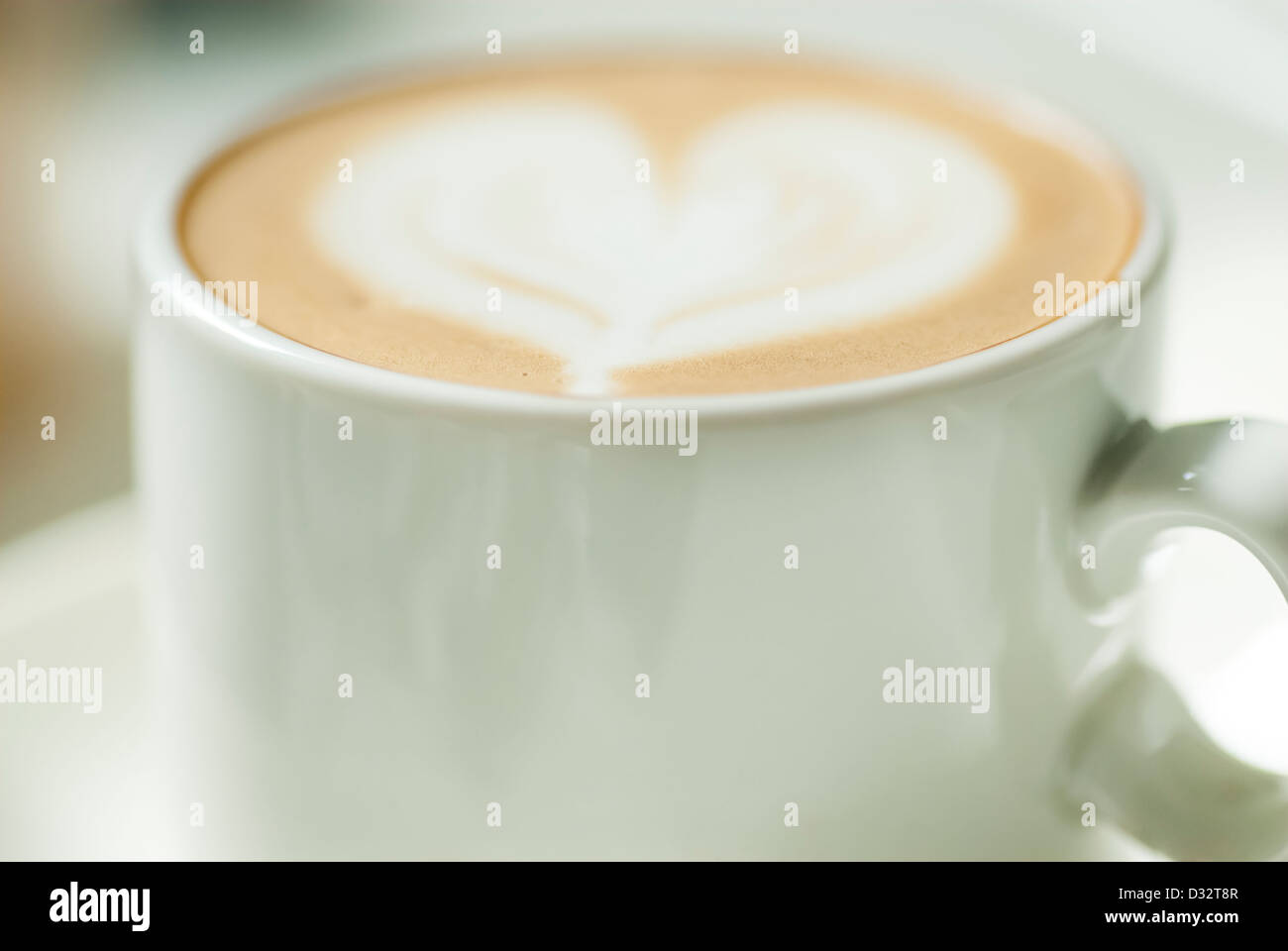 Kleine Kaffeetasse mit Herz-Design in der Milch. Stockfoto