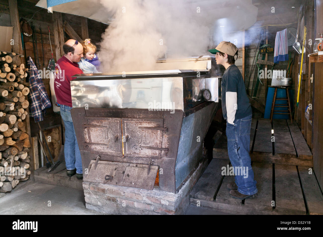 Familien-Peer in einem Verdampfer so dass Ahornsirup während ein Open House bei einem Zuckerhütte Adirondacks New York Stockfoto