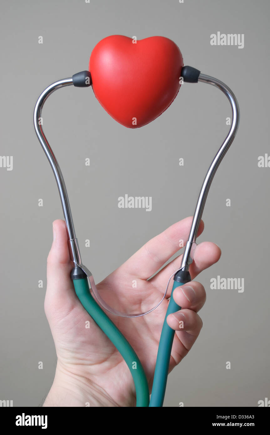 Des Mannes Hand, die ein rotes Herzform und Stethoskop Stockfoto