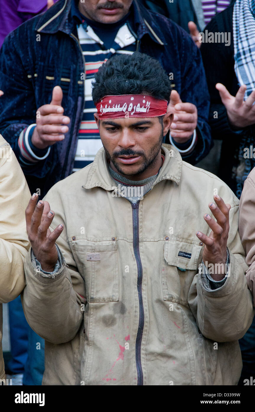 Demonstrator mit Stirnband, das liest: der Aufstand geht weiter betet während einer Protestaktion in Kairo, 31. Januar 2012 Stockfoto