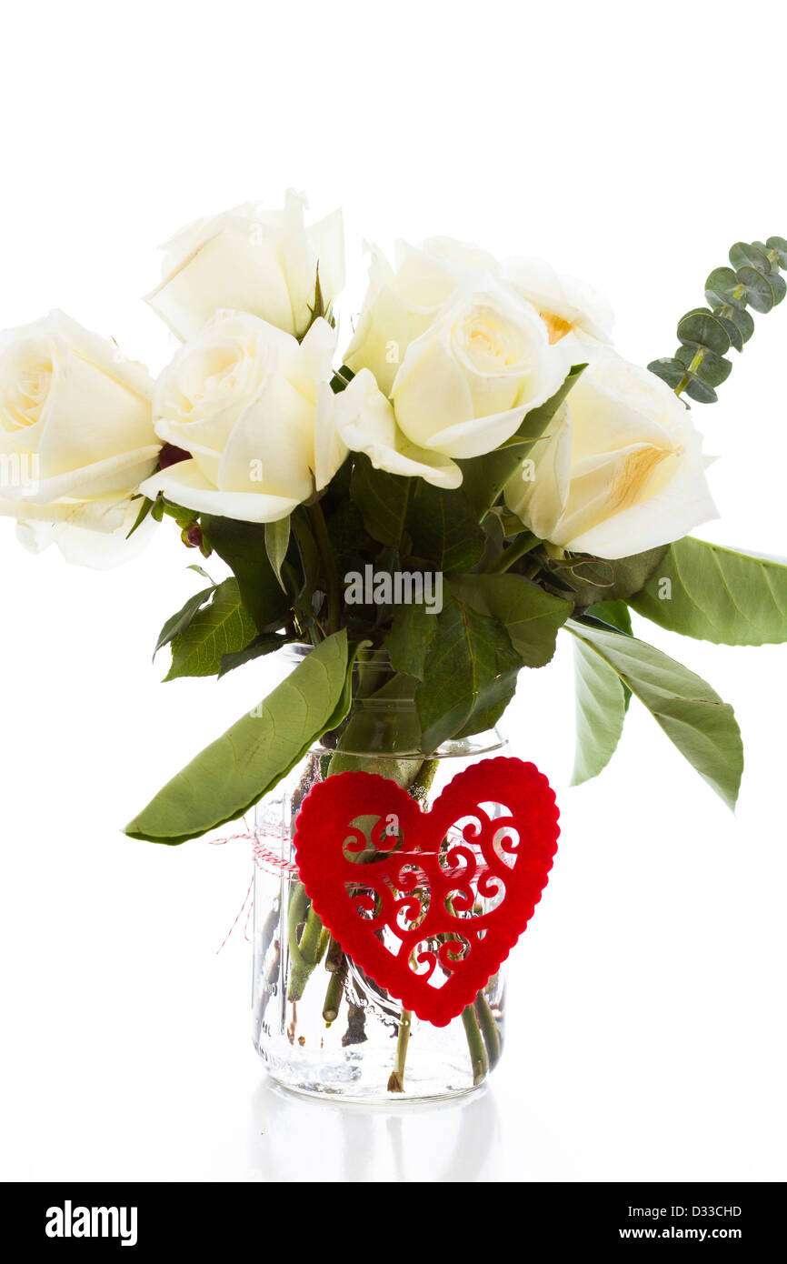 Bouquet von weißen Rosen in Vase mit roten Herzen. Stockfoto