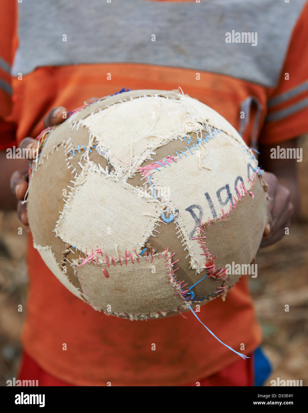 Ein Kind hält eine hausgemachte Fußball- oder Fußball-Kugel Stockfoto