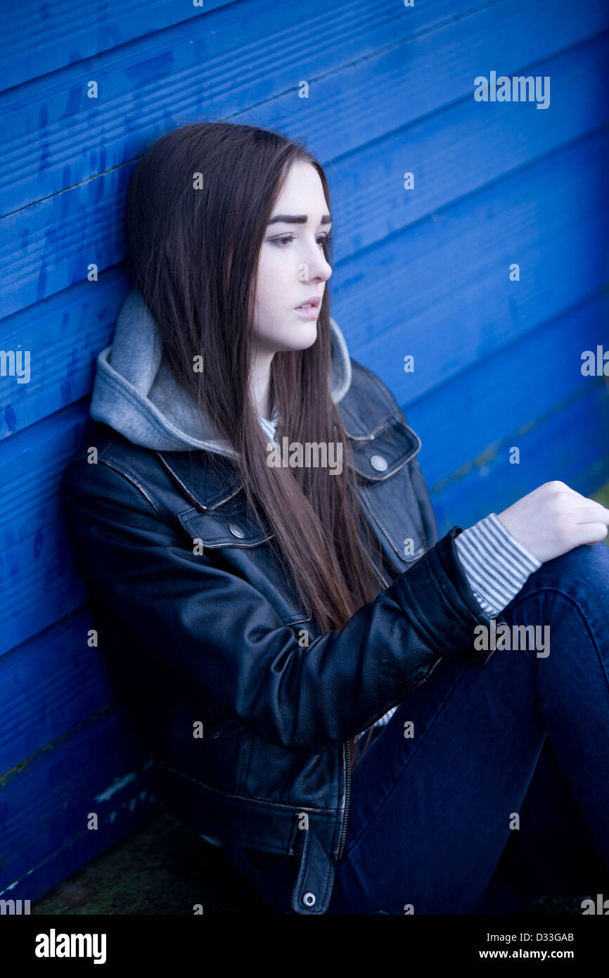 Eine gestörte junge Teenager-Mädchen draußen zu sitzen. Stockfoto