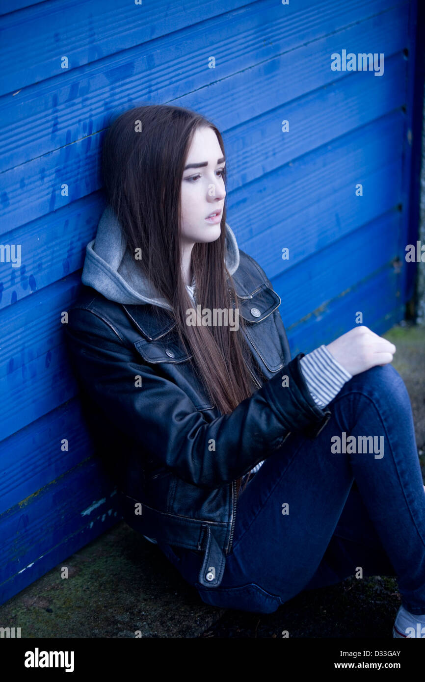 Eine gestörte junge Teenager-Mädchen draußen zu sitzen. Stockfoto