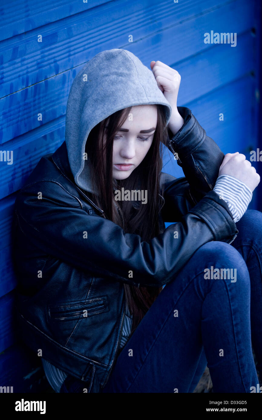 Eine gestörte junge Teenager-Mädchen draußen zu sitzen. Stockfoto