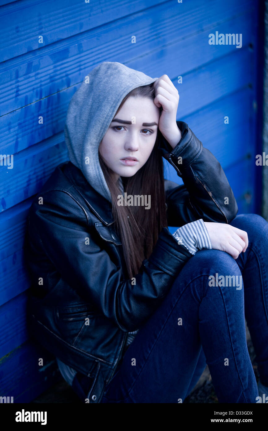 Eine gestörte junge Teenager-Mädchen draußen zu sitzen. Stockfoto