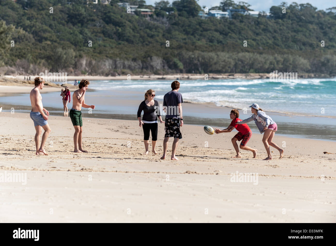 Junge Menschen spielen mit einem Ball auf Zylinder Strand auf North Stradbroke Island in Queensland, Australien Stockfoto