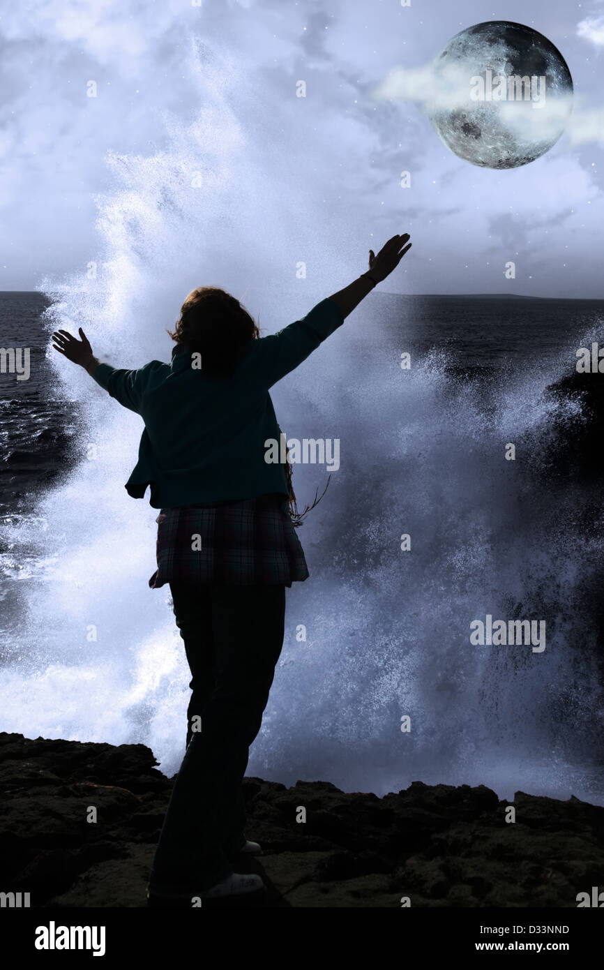eine einsame Frau, hob die Arme in Ehrfurcht vor der mächtige Welle und Vollmond am Rande der Klippen in County Clare Irland Stockfoto
