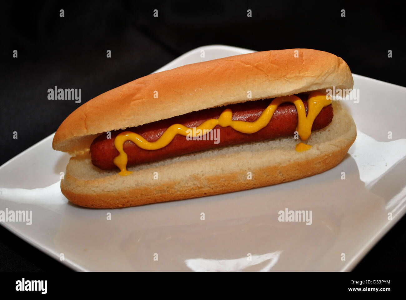 Senf auf einem Hotdog über schwarz Stockfoto