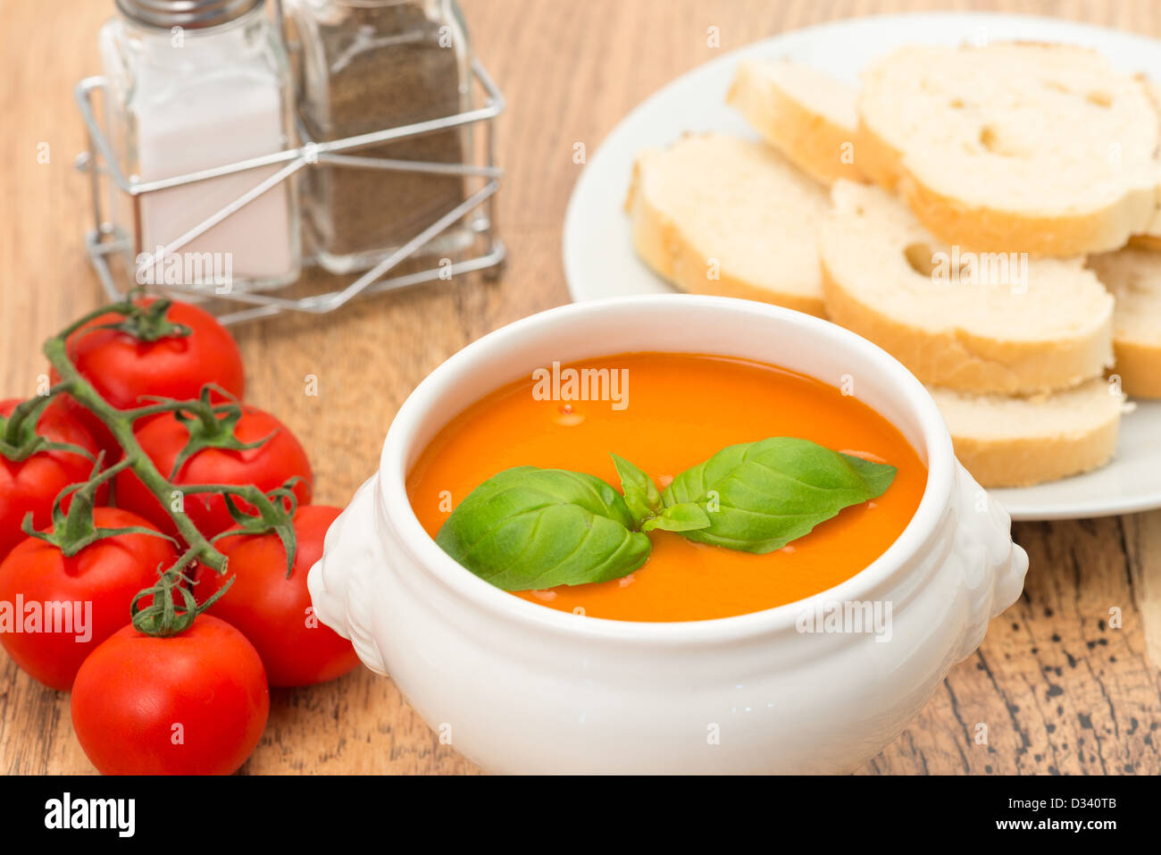 Eine Schüssel mit Tomatensuppe mit frischen Tomaten und auf der Rebe und knusprigem Brot. Stockfoto