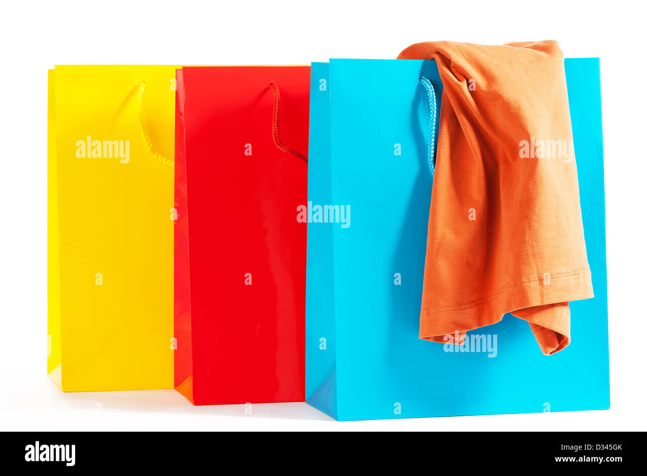 drei bunte Einkaufstaschen mit einem orangefarbenen t-Shirt auf weißem Hintergrund Stockfoto
