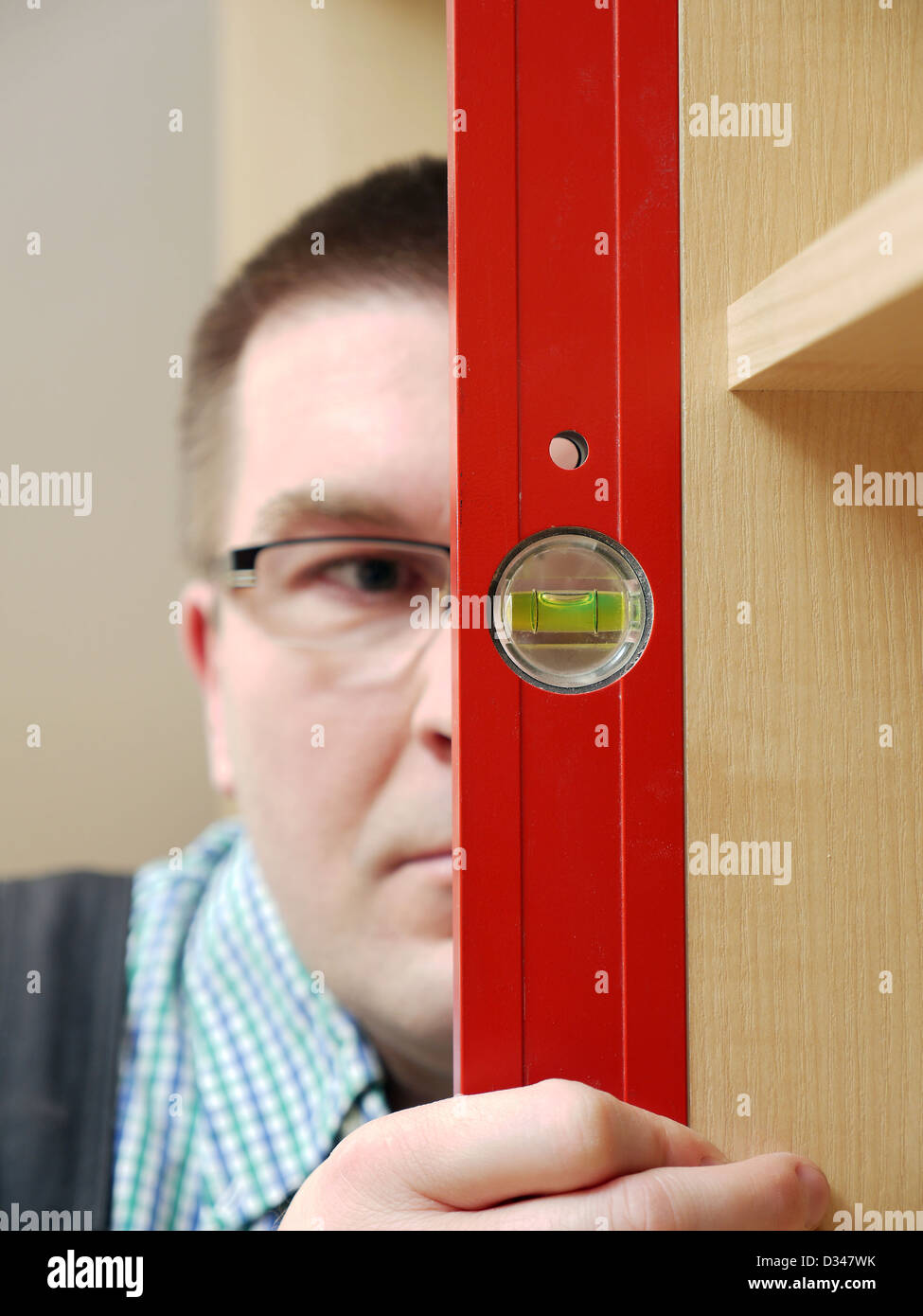 Closeup Aufnahme von Carpenter betrachten Wasserwaage zu messen, um zu überprüfen, vertikale Positionierung der Möbel - geringe Schärfentiefe Stockfoto