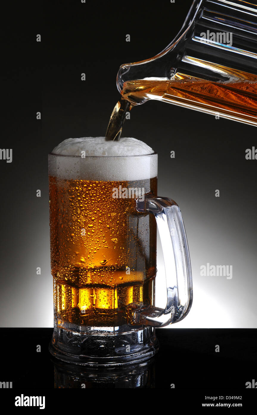 Nahaufnahme von einem Bierkrug aus einem Krug gießt kaltes Bier in das Glas gefüllt wird. Stockfoto