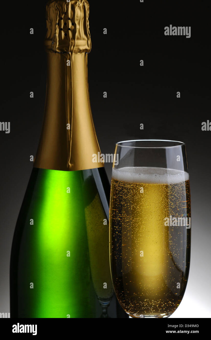 Nahaufnahme einer Flasche Champagner und Querflöte auf eine leichte bis dunkelgrauen Hintergrund. Stockfoto