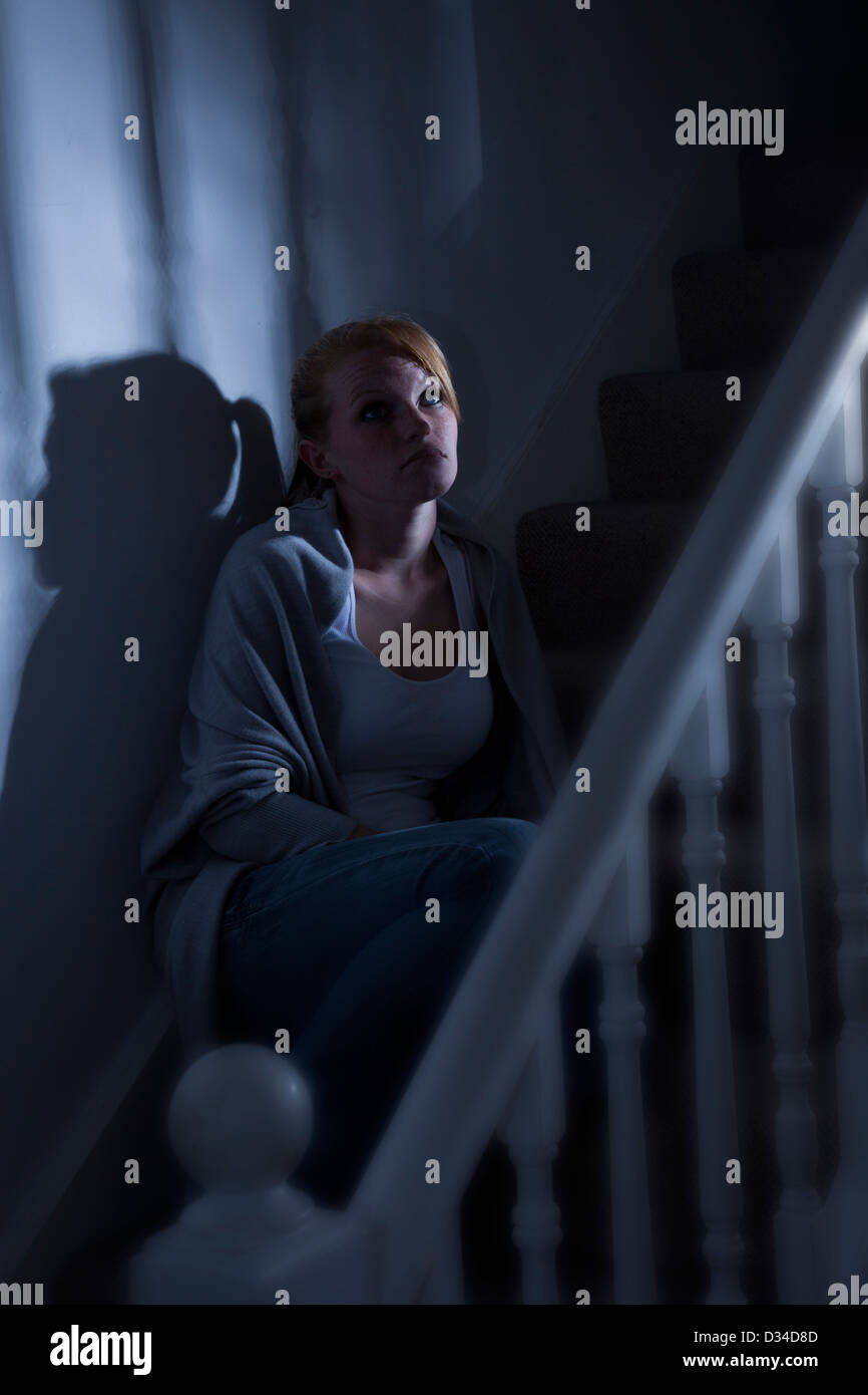 Eine junge Frau, Anfang der zwanziger Jahre oder späten Teenager sitzen allein auf den Stufen, blickte nachdenklich. Stockfoto