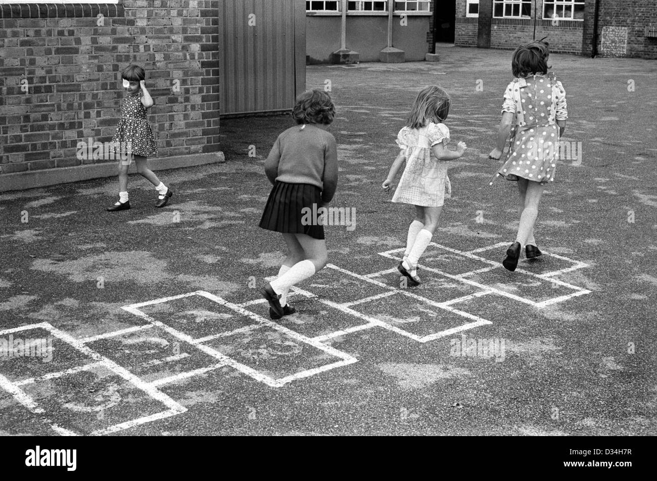 Grundschule Spielplatz Hoppscotch Hop scotch. Mädchen spielen zusammen. South London. 1970s Großbritannien. Das junge Mädchen links trägt einen Augenfleck. HOMER SYKES Stockfoto