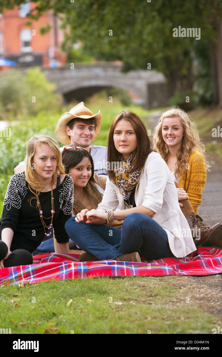Eine Gruppe von jungen und Mädchen sitzen auf der Picknickdecke. Stockfoto