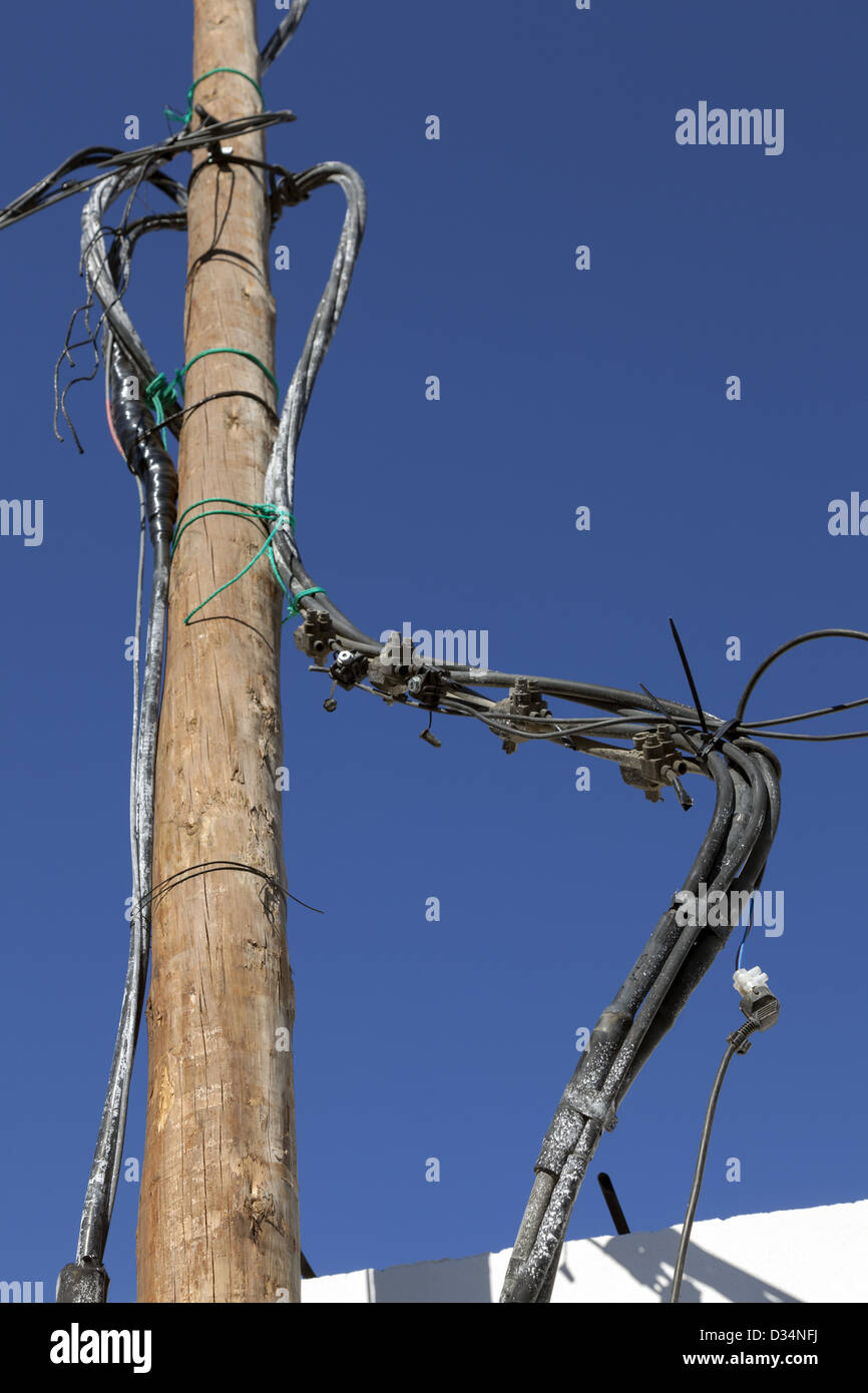 Dangerous verdreht und Durcheinander von elektrischen Kabeln, Kreuzungen und hingen von Holzstange ausgesetzt Stockfoto