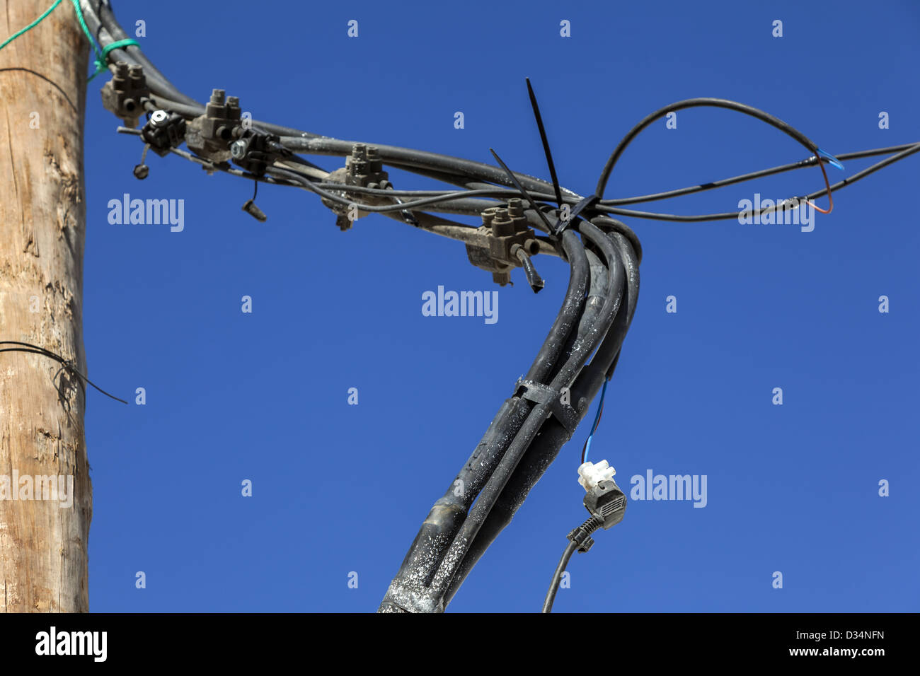 Dangerous verdreht und Durcheinander von elektrischen Kabeln, Kreuzungen und hingen von Holzstange ausgesetzt Stockfoto
