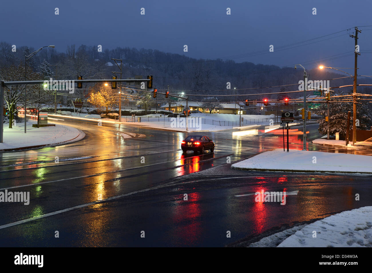Stadt-Kreuzung im Winter mit nassen Straßen & Schnee Stockfoto