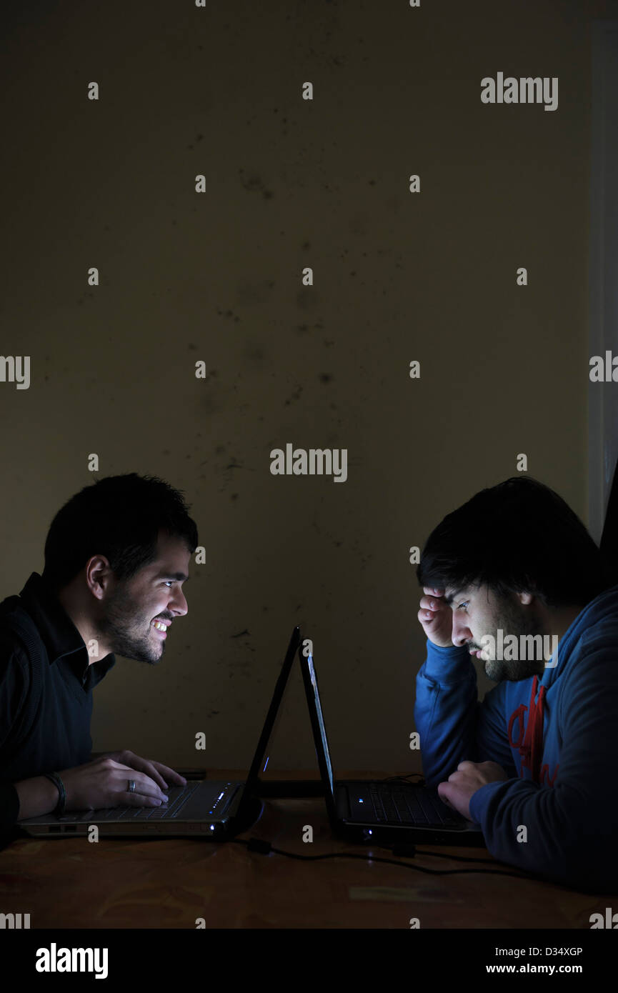 Zwei junge Männer, die mit Laptops von Angesicht zu Angesicht Stockfoto