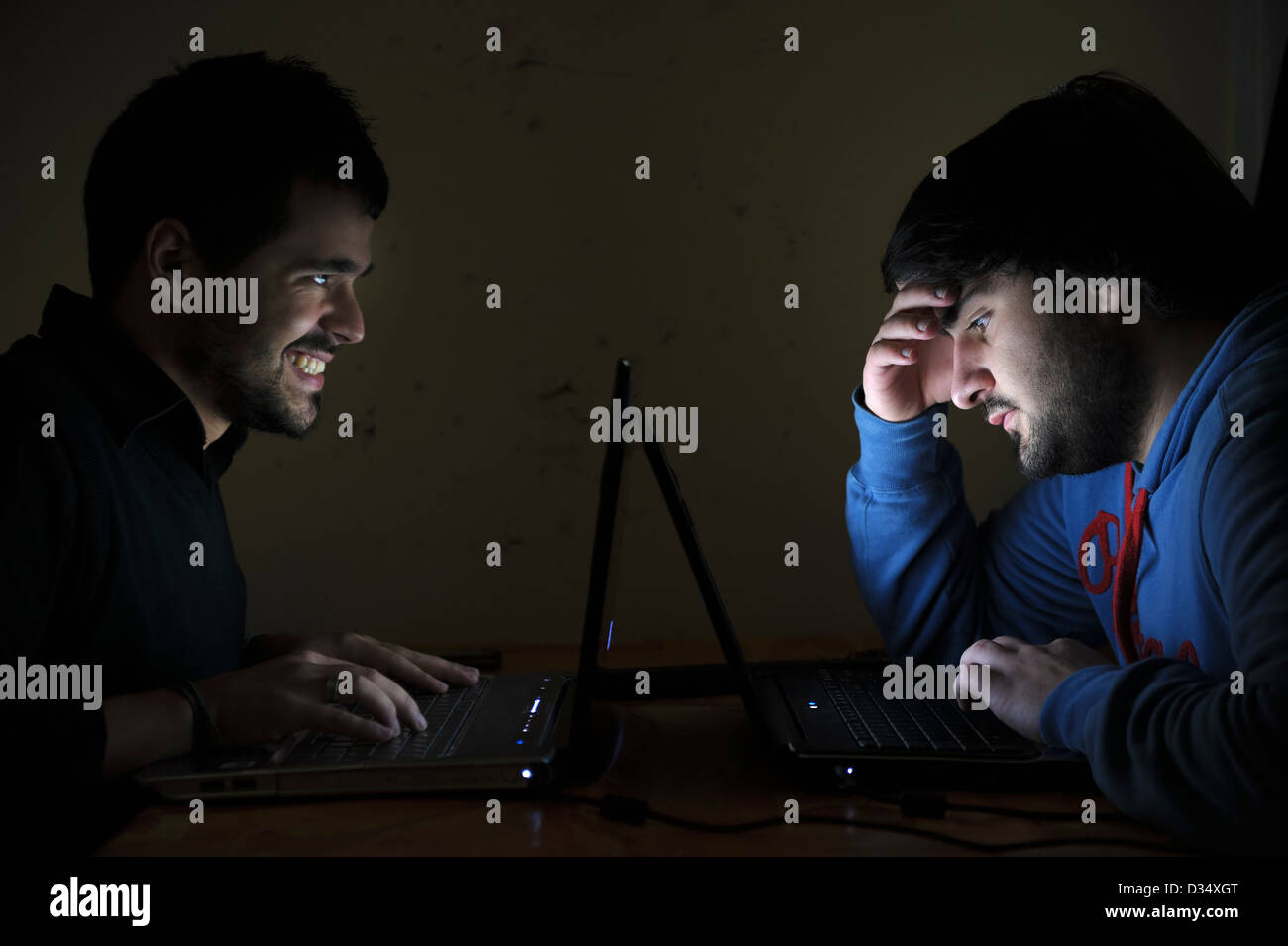Zwei junge Männer, die mit Laptops von Angesicht zu Angesicht Stockfoto