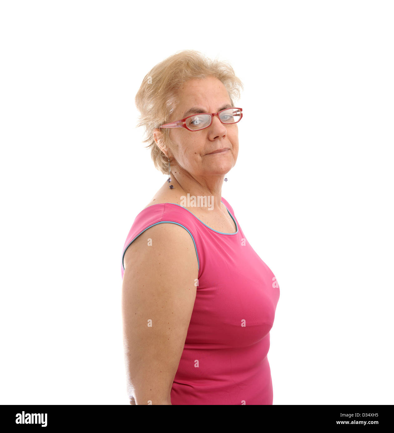 Selbstbewusste mittlere gealterte Frau trägt ein rosa ärmelloses Hemd mit Blick auf ihre Rechte Schulter isoliert auf weißem Hintergrund Stockfoto