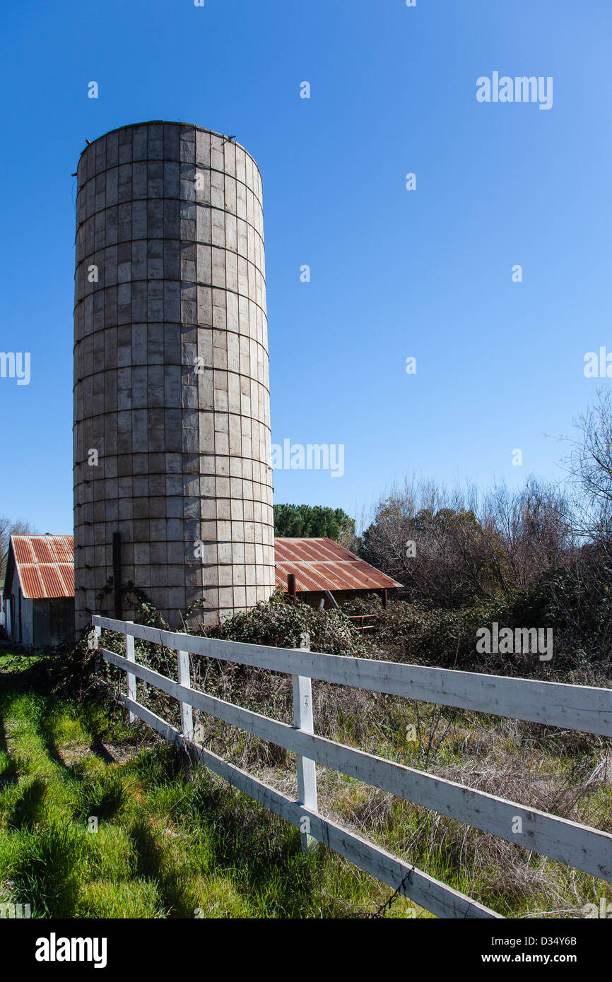 Ein Betonsilo und verrosteten Metalldach ein landwirtschaftliches Gebäude in den Hintergrund und weißen Schiene Zaun im Vordergrund in Santa Ynez, Kalifornien. Stockfoto