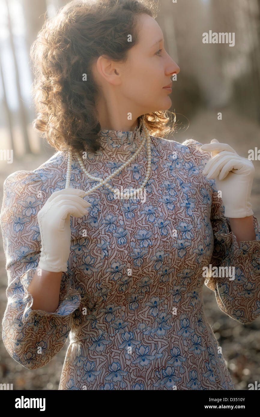 eine Frau in ein Vintage-Kleid mit Handschuhen und einer Perlenkette Stockfoto