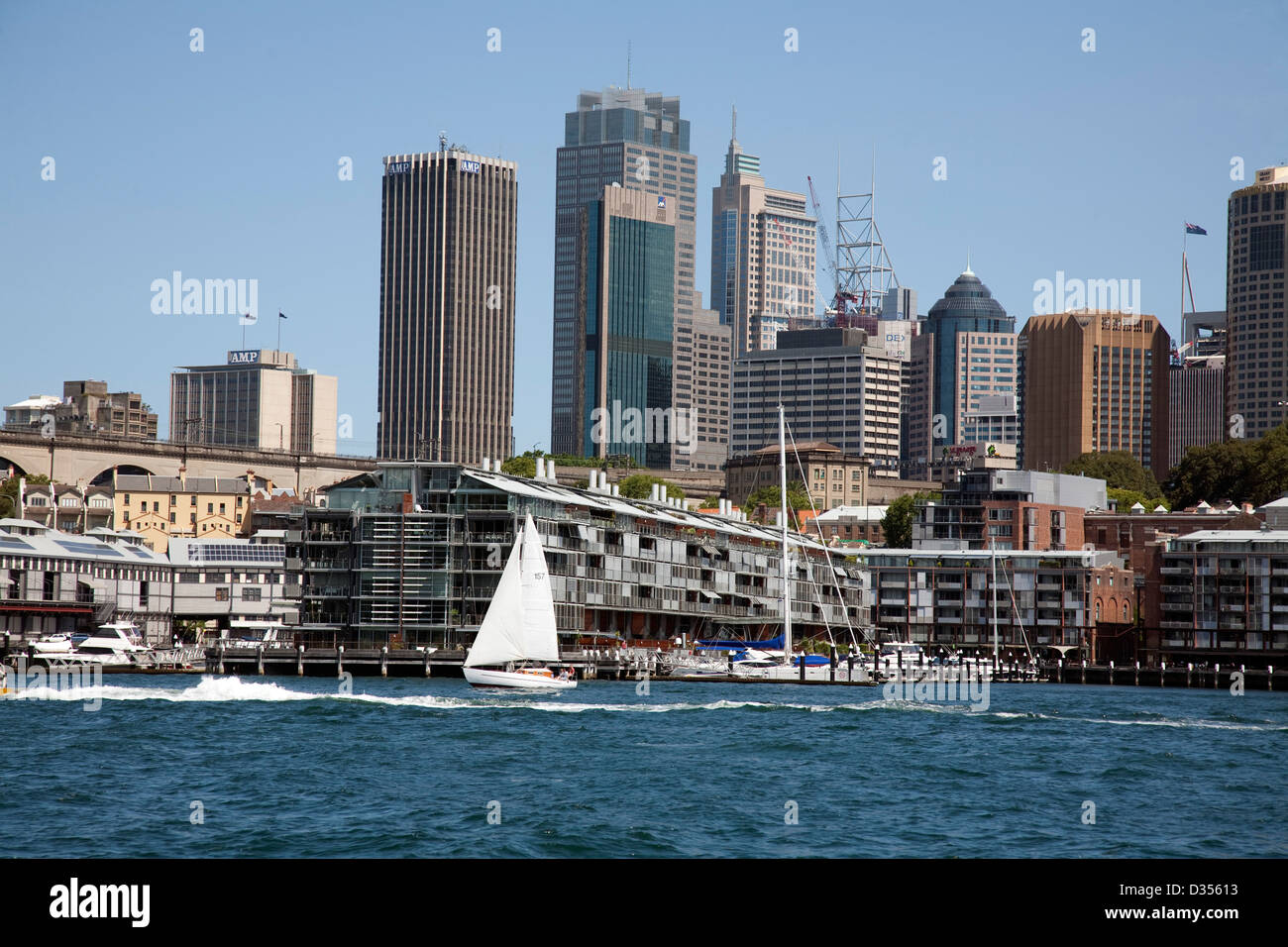 Yacht segeln vorbei an Wohnungen Walsh Bay Wharf Entwicklung mit Sydney CBD Skyline im Hintergrund. Stockfoto