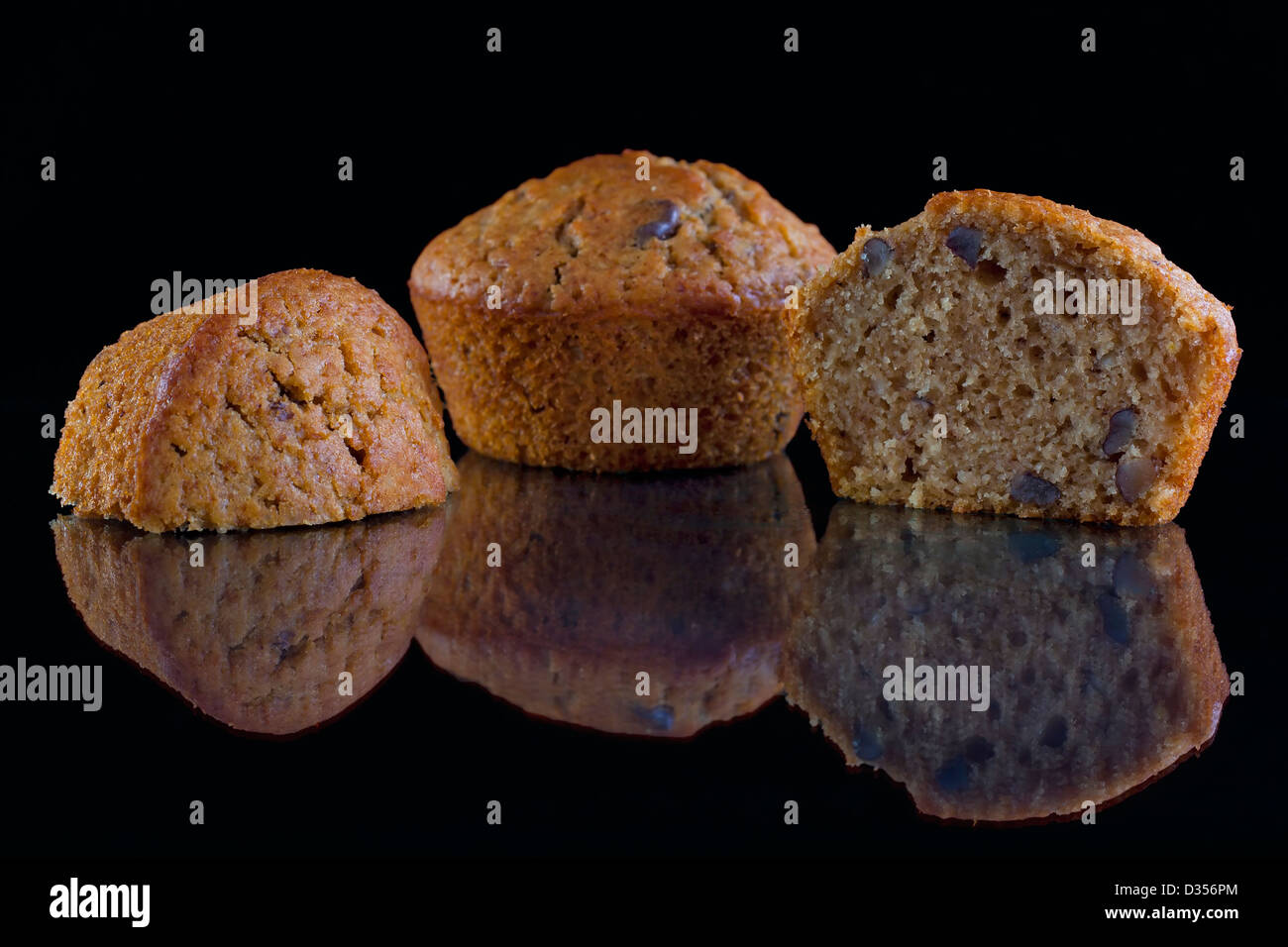 Frisch gebackene Walnuss-Muffins auf einer reflektierenden Oberfläche schwarz Stockfoto