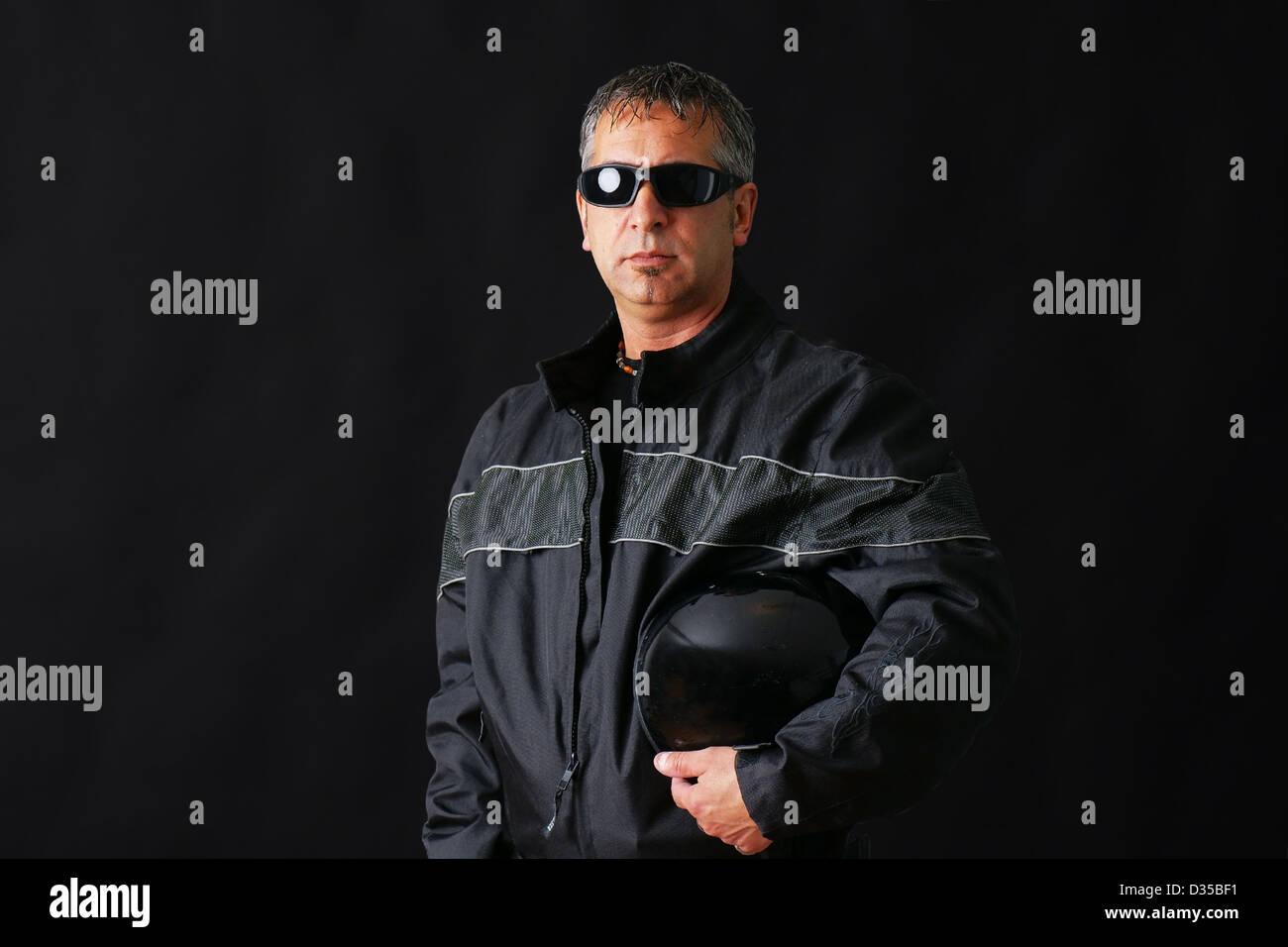 Harter Kerl mit Biker-Jacke und Helm, könnte kriminellen, mittlere gealtert, Studio über Schwarz erschossen. Stockfoto
