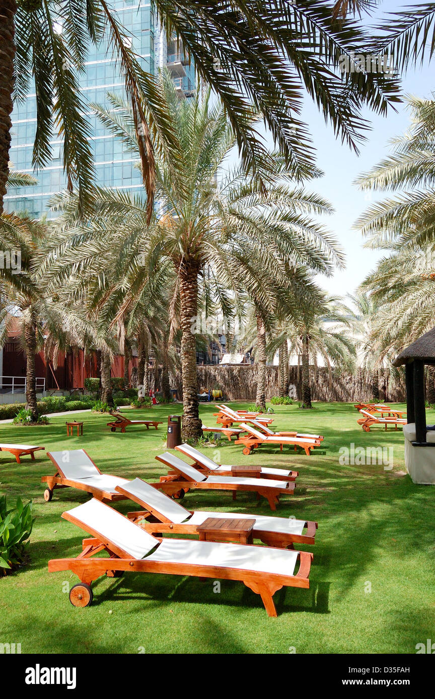 Sonnenliegen auf dem grünen Rasen und Palmen Baum Schatten in Luxus-Hotel, Dubai, Vereinigte Arabische Emirate Stockfoto