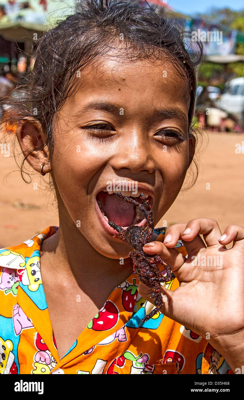 Kambodschanisches Mädchen isst eine frittierte Tarantel. Panierte, tiefe gebratene Vogelspinnen sind zum Verkauf an Skuon, bekannt als "Spiderville Stockfoto