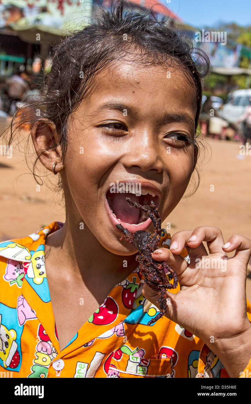 Kambodschanisches Mädchen isst eine frittierte Tarantel. Panierte, tiefe gebratene Vogelspinnen sind zum Verkauf an Skuon, bekannt als "Spiderville Stockfoto