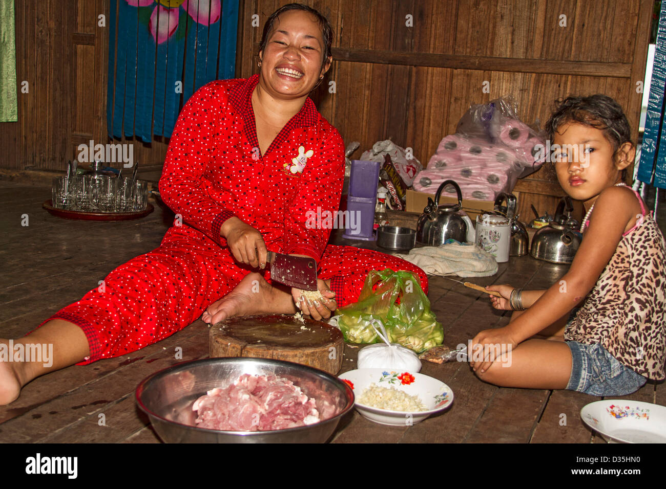 Junge Frau bereitet Schweinefleisch, Knoblauch und Gemüse für das Abendessen auf der Insel Koh Trong über den Mekong River von Kratie, Kambodscha. Stockfoto