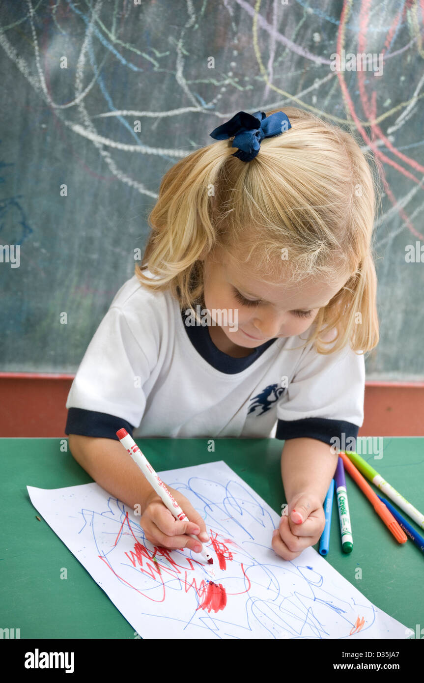 Glücklich lächelnd attraktive blondes Kleinkindes Mädchen außerhalb im sonnigen Kindergarten Schule bilden und Formen zeichnen lernen Stockfoto