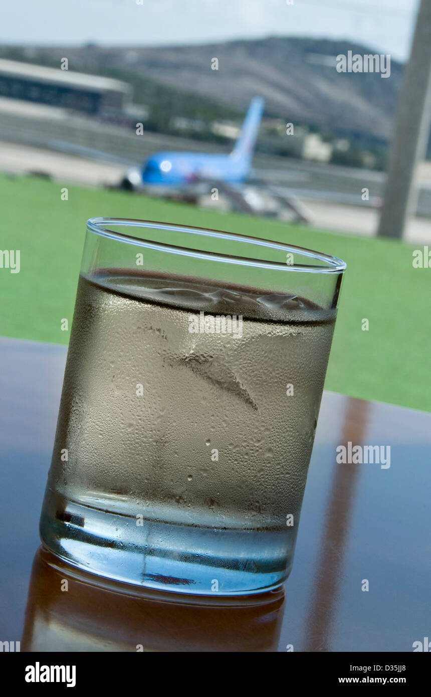 Großes Glas mit Eis im Airport-Business-Lounge mit Flugzeugen auf Stand im Hintergrund sehr trockener Wermut Stockfoto