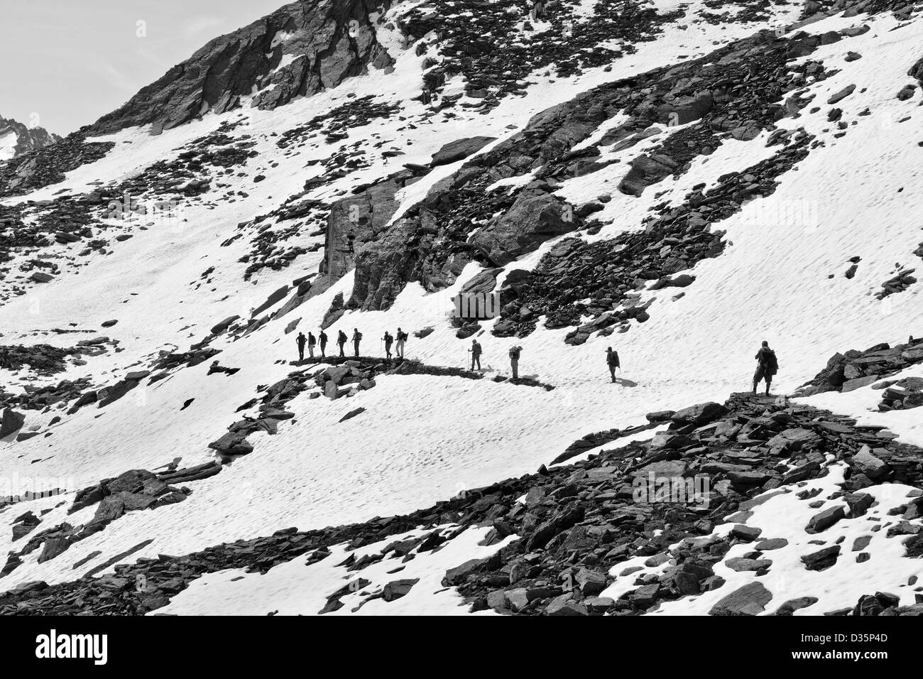 Wanderer zu Fuß auf alpinen Schnee bedeckt Trail in Valnontey, Nationalpark Gran Paradiso, Graian Alpen - Italien (Schwarzweiß) Stockfoto