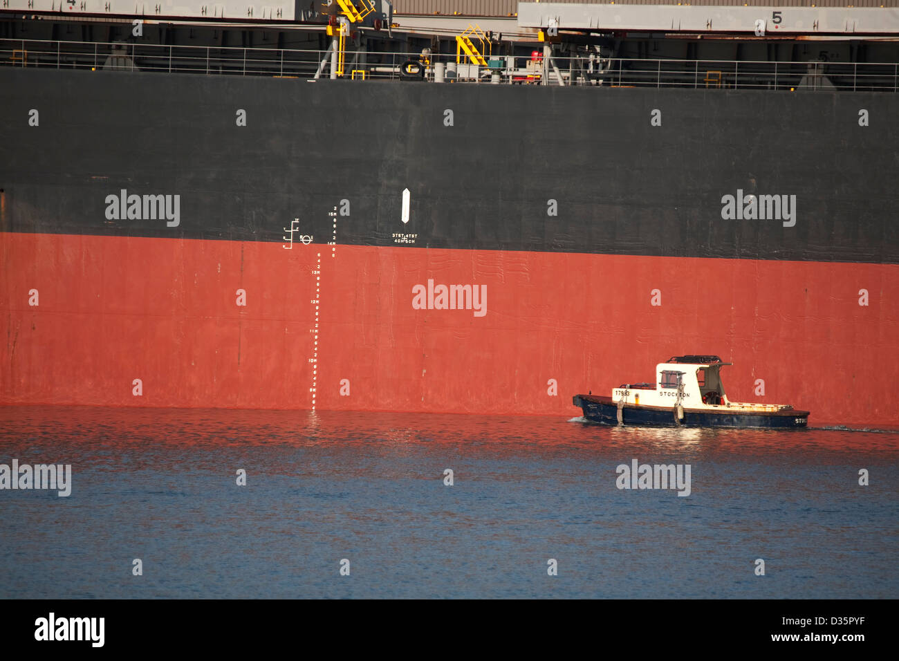 Maritime Arbeitskraft Schiff in den Schatten gestellt ist neben der riesigen Massengutfrachter, die Kohle in Newcastle Australien schwebt. Stockfoto