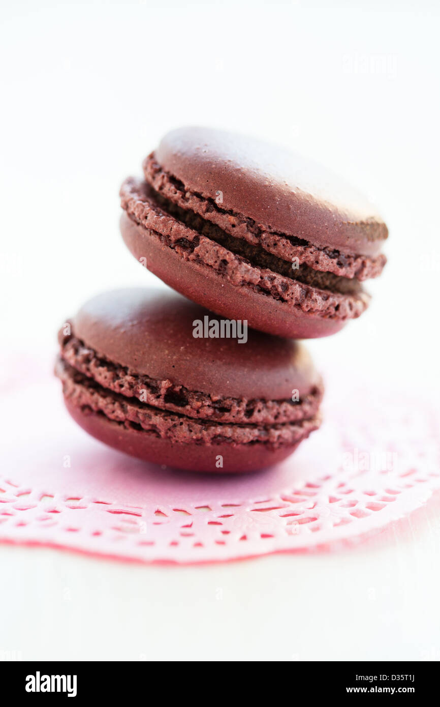 Nahaufnahme von zwei Schokoladen-Makronen auf dekorativen rosa Matte Stockfoto