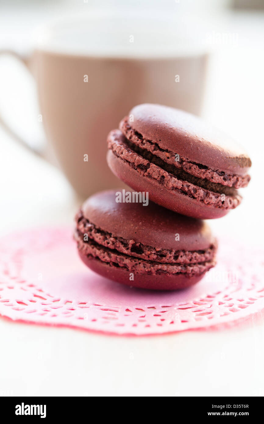 Nahaufnahme von zwei Schokoladen-Makronen mit Tasse im Hintergrund Stockfoto