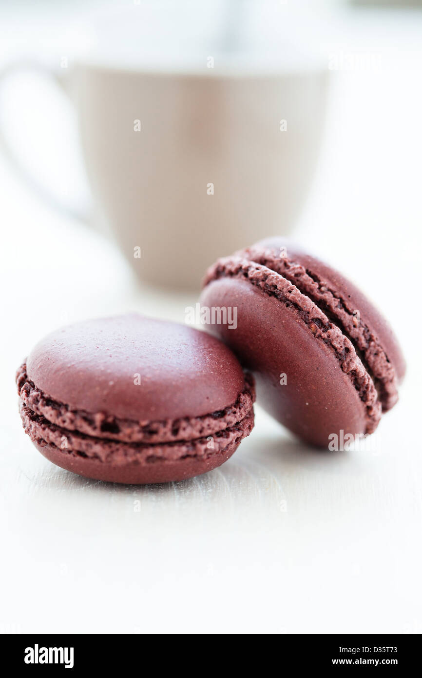 Nahaufnahme von zwei Schokoladen-Makronen mit Tasse im Hintergrund Stockfoto