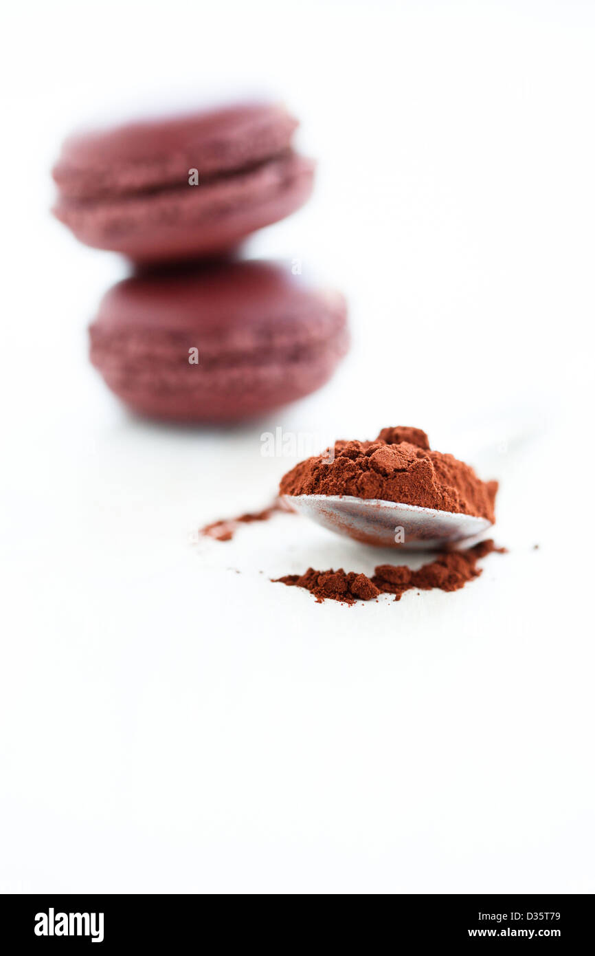 Nahaufnahme des Kakaopulvers in Löffel mit zwei Makronen im Hintergrund Stockfoto