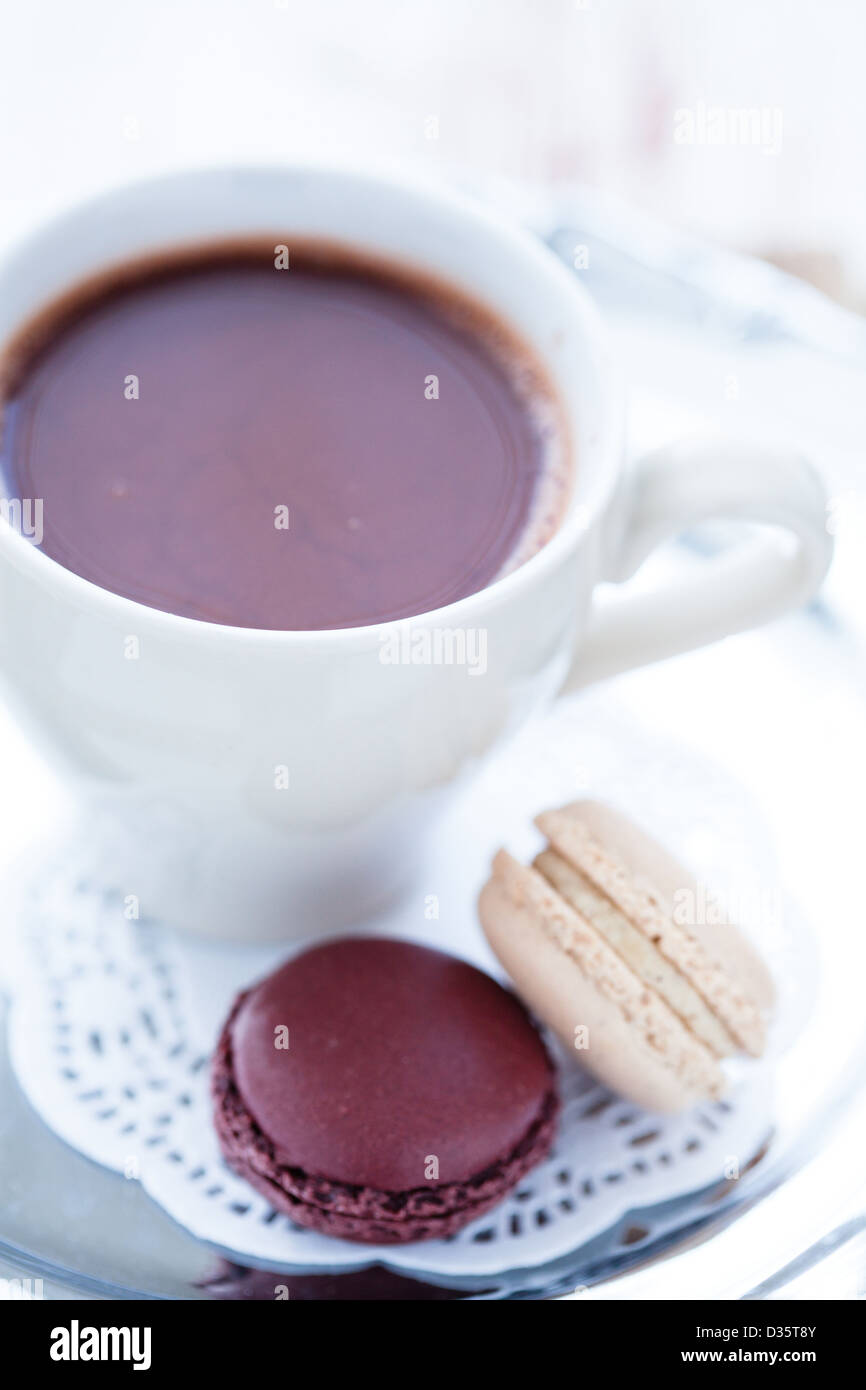 Nahaufnahme der Tasse heiße Schokolade mit zwei Makronen auf einem Holztisch Stockfoto