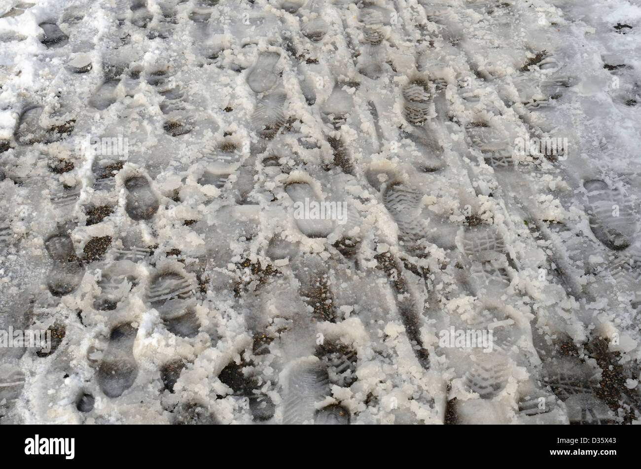 Fußspuren im Schneematsch auf einem Pflaster Stockfoto